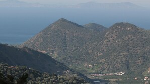 Eine gebirgige Landschaft mit Blick auf das Meer und ferne Hügel.