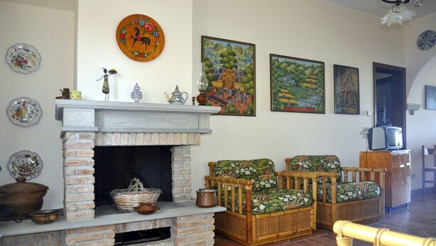 Un soggiorno con camino in mattoni, mobili in vimini e decorazioni alle pareti.