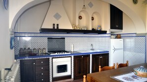 Una cucina con un piano di lavoro blu, un fornello bianco e mobili impiallacciati in legno scuro.