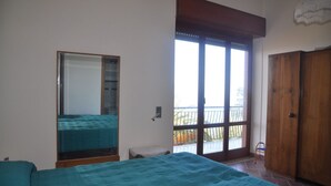 Una camera da letto con un letto, un armadio, una finestra e un balcone.