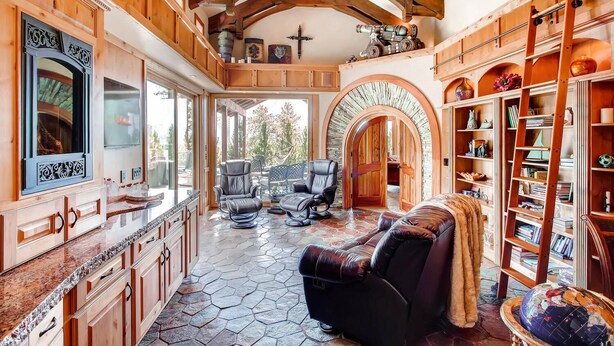 A spacious living area with a fireplace, leather seating, and a bookshelf. - Castle with Pikes Peak Views & Hot Tub
Bus. license #008672 (Woodland Park)