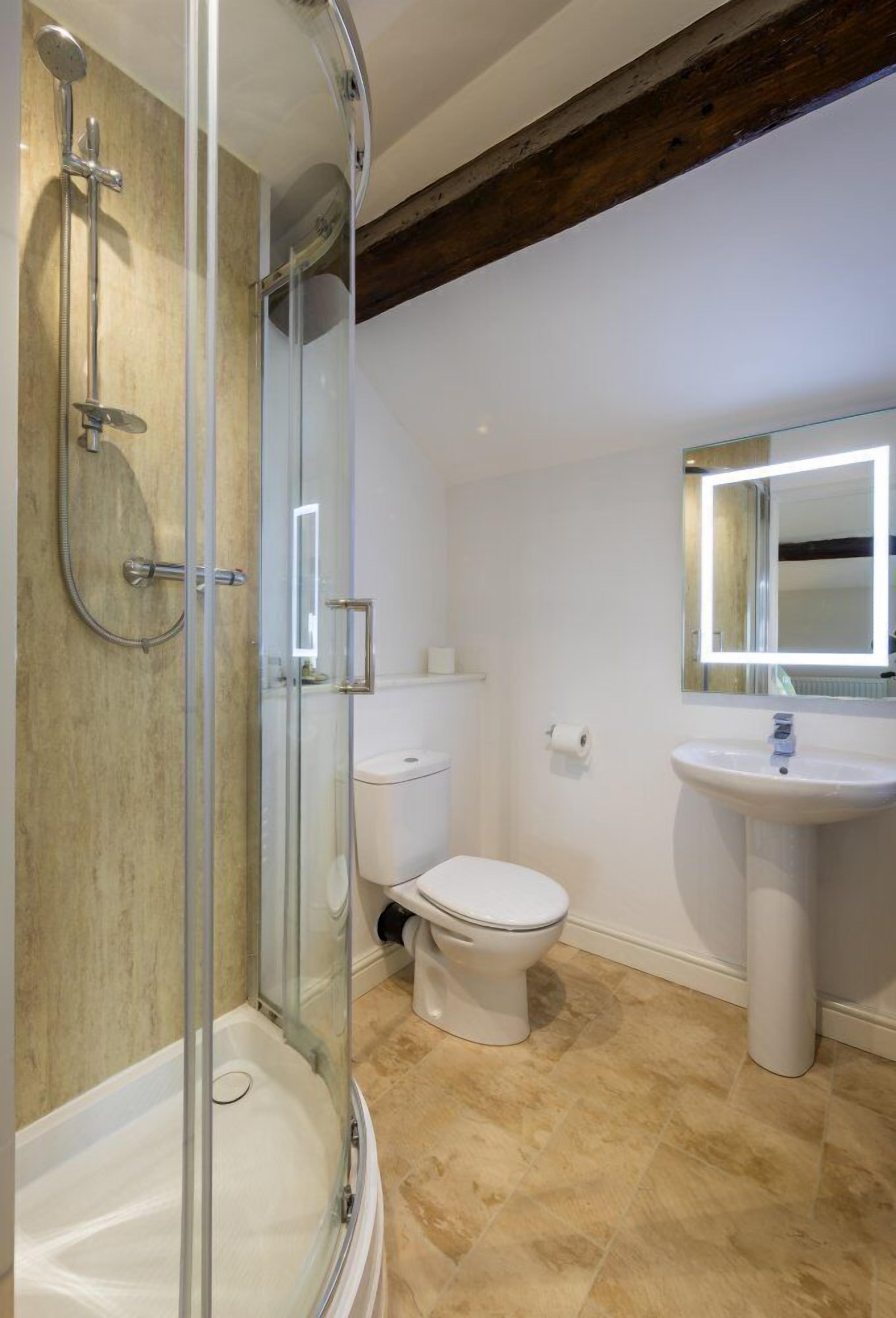 A bathroom with a glass-enclosed shower, a white toilet, and a pedestal sink.