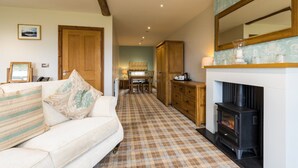 A cozy living room with a fireplace, a checkered floor, and a dining area in the background. - The Inn at Ravenglass (Ravenglass)