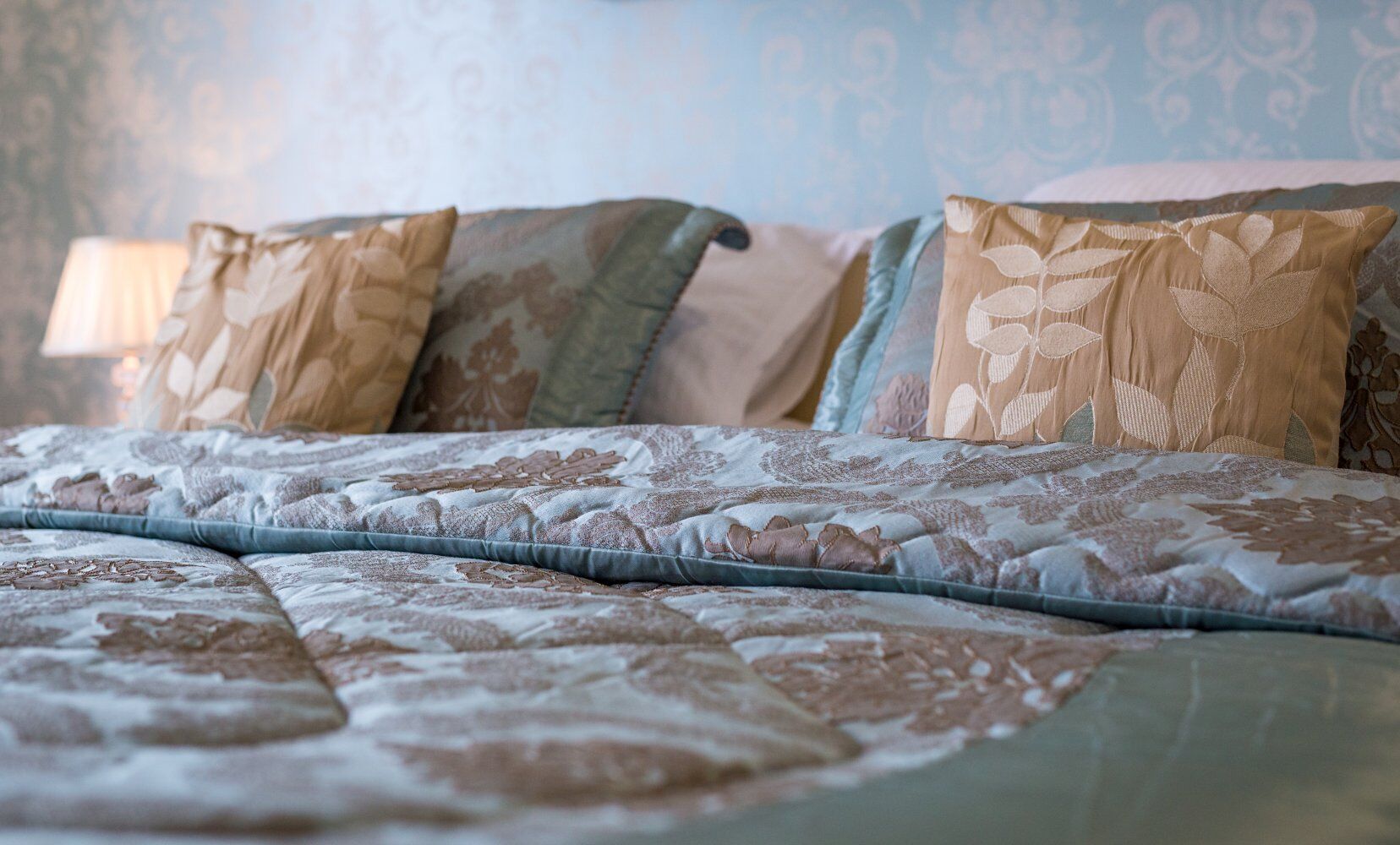 A bed with a patterned bedspread and multiple pillows.