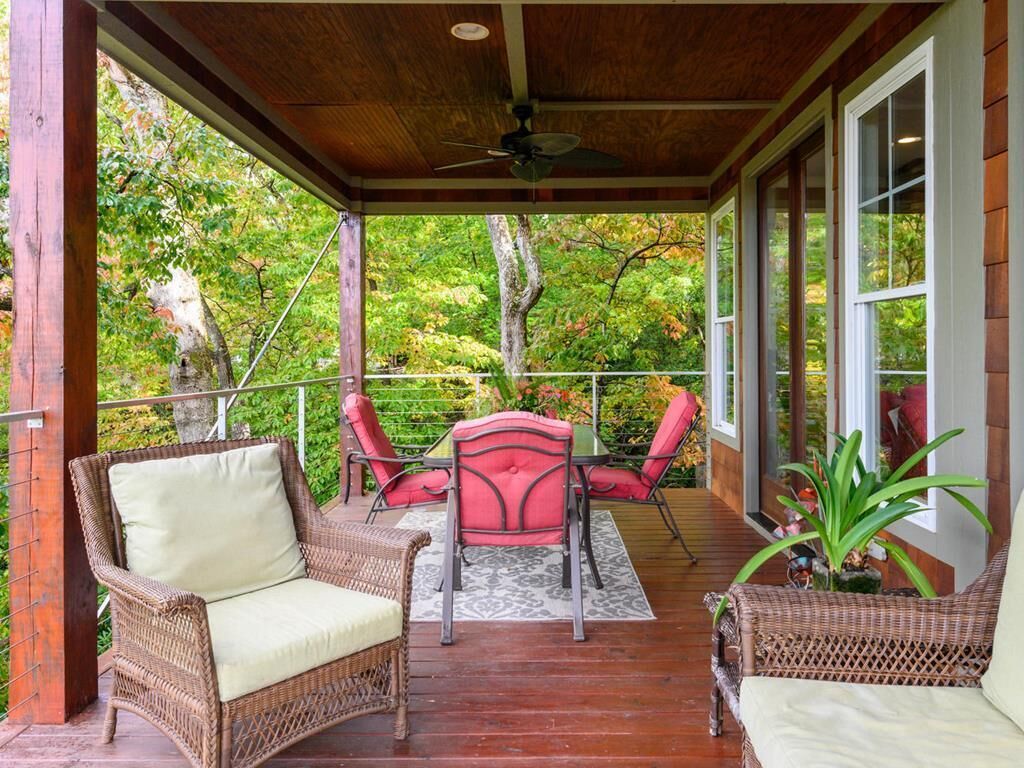 Eine überdachte Terrasse mit Korbmöbeln und einem Deckenventilator.