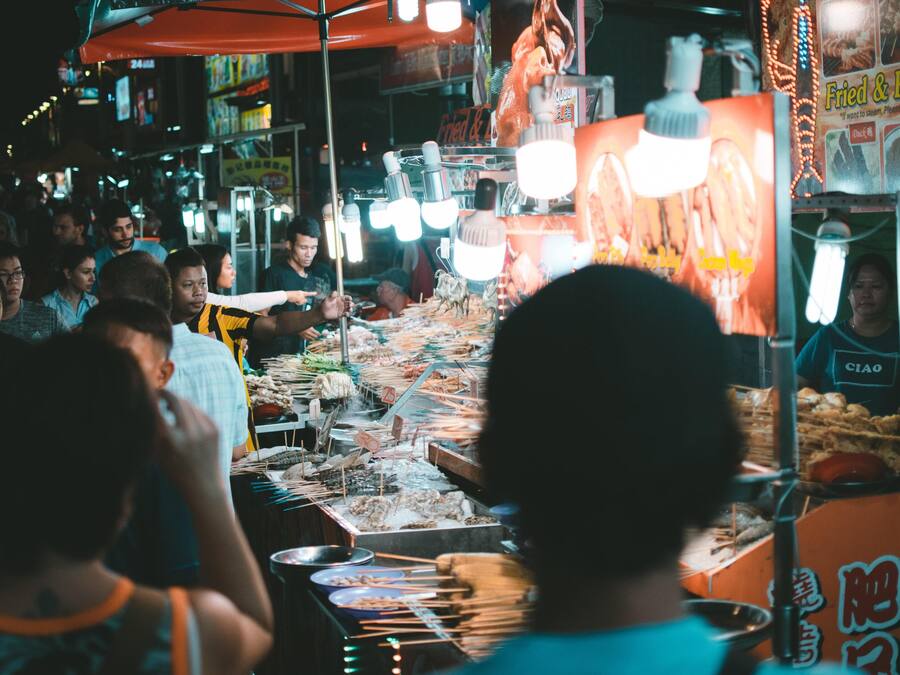 A busy street food market with various food stalls and people.