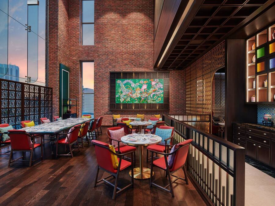 A restaurant with brick walls, a large mural, and a view of the cityscape.
