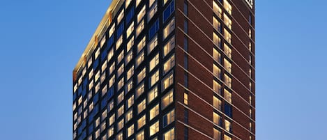 A tall, modern hotel building with a clear blue sky in the background.