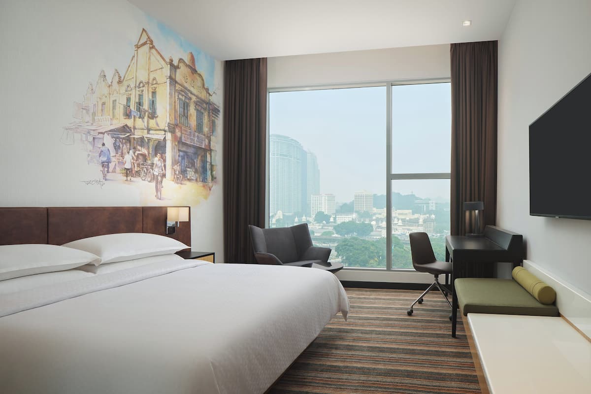 Une chambre d’hôtel avec un grand lit, un bureau, une chaise, un canapé et une télévision.