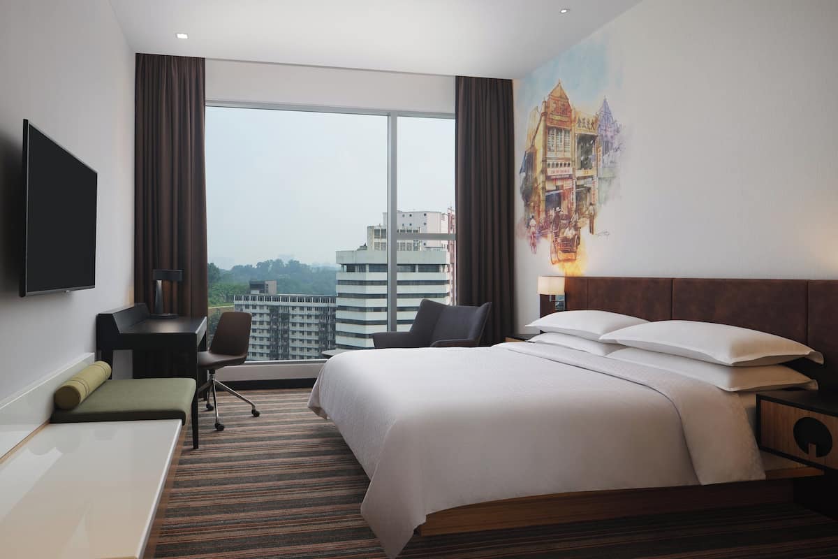 Une chambre d’hôtel avec un grand lit, un bureau, une chaise, une télévision et une vue sur le paysage urbain.