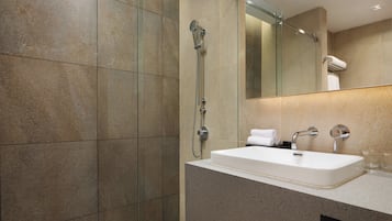 A modern bathroom with a glass-enclosed shower, a white sink, and a large mirror.