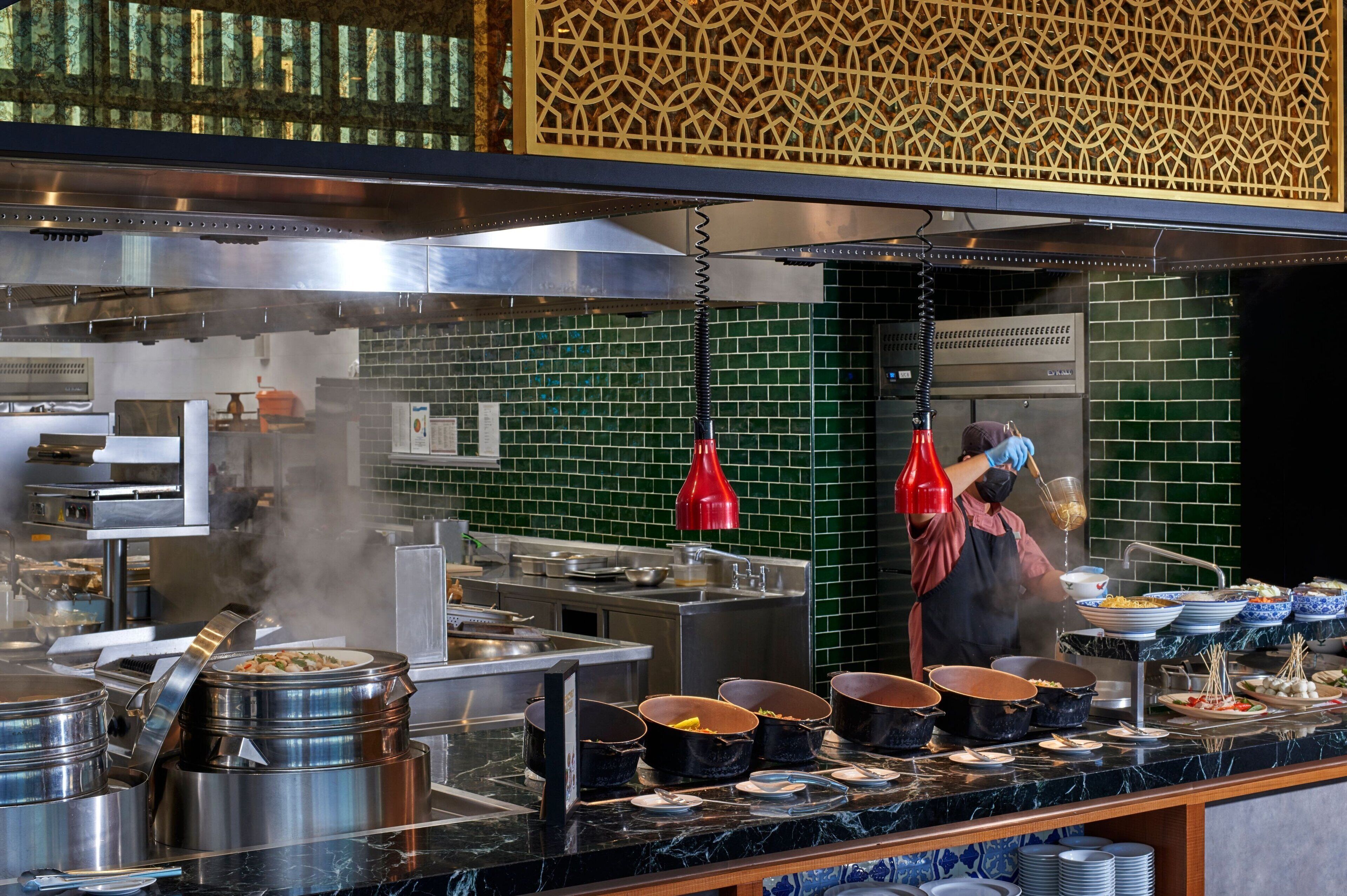 A buffet setup with various dishes and cooking equipment.