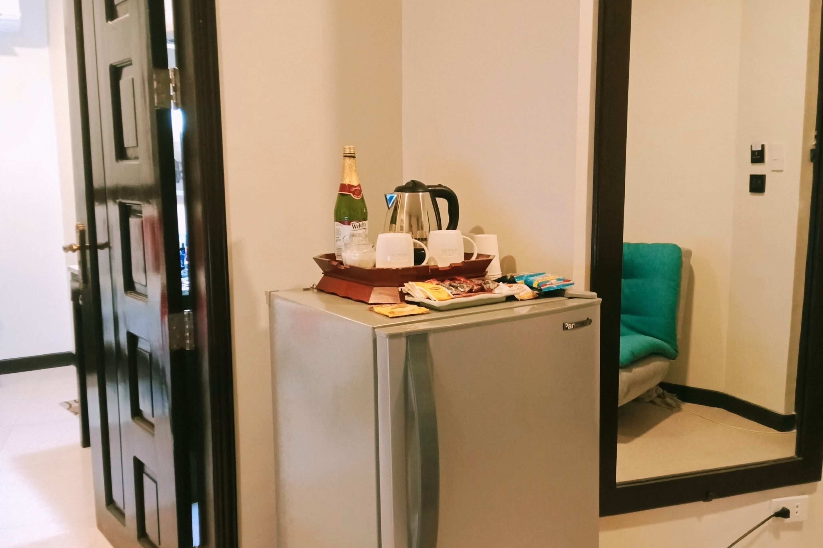 Un mini-bar contenant une bouteille de champagne, une machine à café et diverses collations.