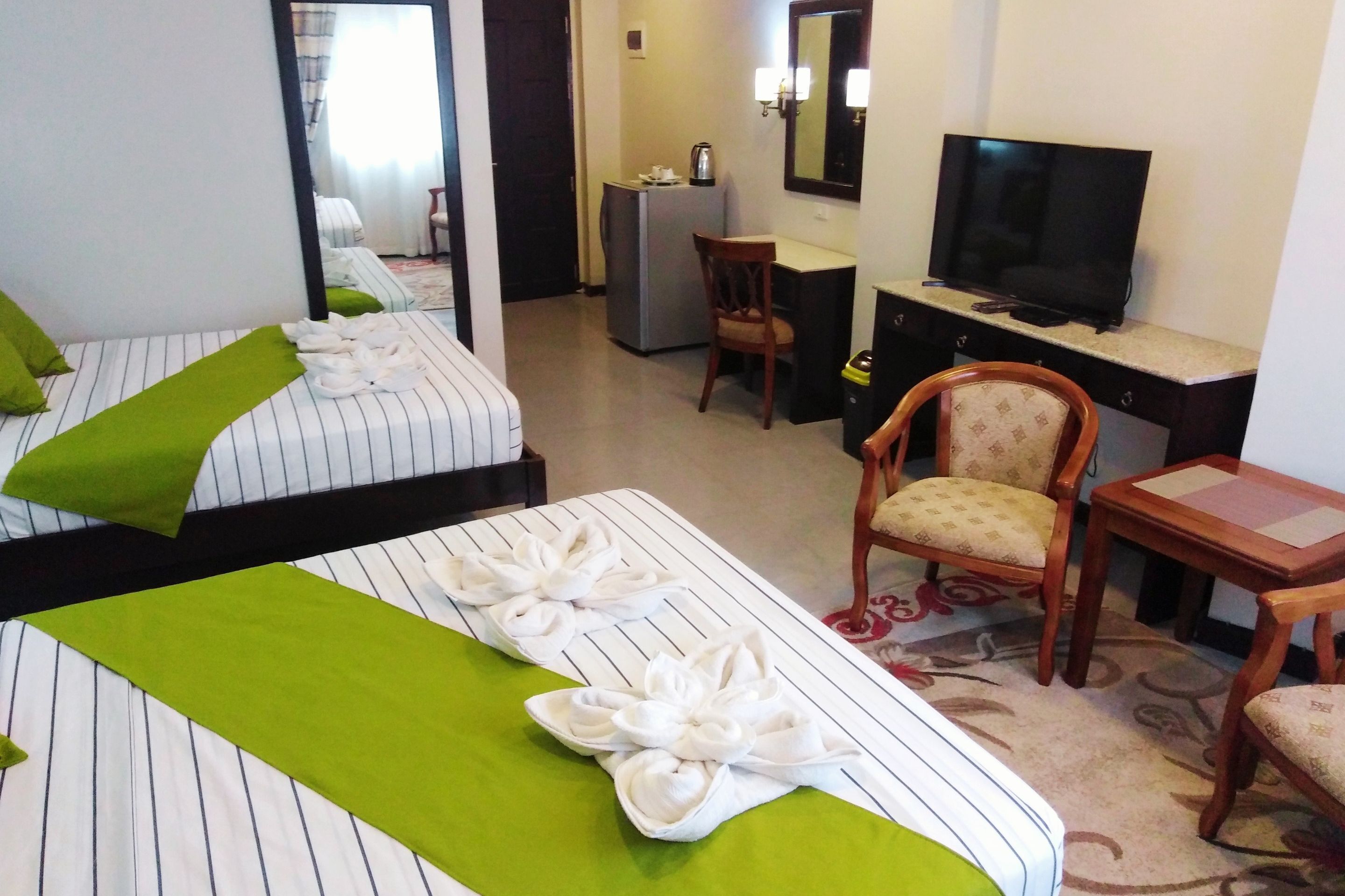 Une chambre d’hôtel avec deux lits, un bureau, une télévision et une chaise.