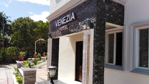 Das Hotel Venezia mit einer Steinfassade, einem einladenden Eingangsbereich und Pflanzen in Kübeln.