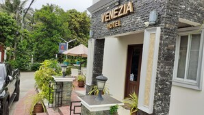 Das Venezia Hotel mit einer Steinfassade, Außenbereich mit Sitzgelegenheiten und Topfpflanzen.