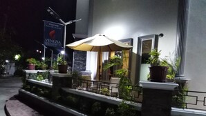 Ein Hotel Eingang mit freundlichem Schild, Sitzbereich im Freien und Topfpflanzen.