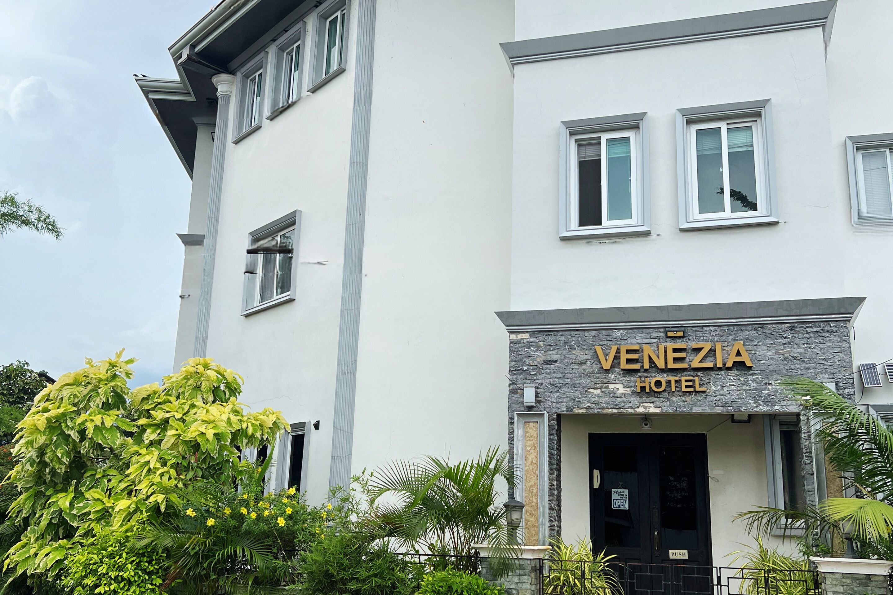 A hotel named 'Venezia Hotel' with a modern facade, large windows, and a stone accent wall.