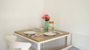 A small dining table with plates, glasses, and a vase of flowers.