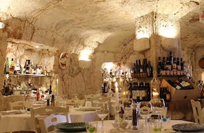 A restaurant with tables set for dining, wine bottles on shelves, and a stone cave-like interior. - Villa Stella Cadente. Privacy, Torre Guaceto Reserve at 4 km. Wow what a peace! (Serranova Di Carovigno)