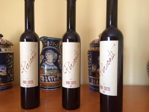 Four bottles of wine with labels, one of which has a ceramic mug with a design. - B&B Azienda Perconti (Cellino Attanasio)