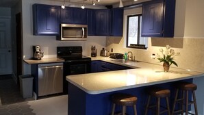 A modern kitchen with dark blue cabinets, stainless steel appliances, and a central island with bar stools. - LAKEFRONT,Swim,enjoy&relax,7kayaks,SUP,paddlboat,firepit,PA,cabin,Fun,  (Tobyhanna)