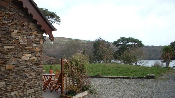 Un bâtiment en pierre doté d’un patio, d’une table et de chaises.