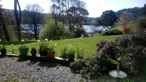 Un jardin agrémenté de plantes en pot, d’une pelouse verdoyante et d’une étendue d’eau en arrière-plan.