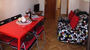 A compact living space with a dining table, chairs, a sofa, a lamp, and a door leading to another room. - Elegance Plaza Mayor with Balcony (Madrid)