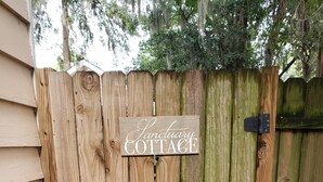A wooden fence with a sign that reads "Sanctuary Cottage."