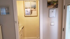 A hallway with a tiled floor, a trash bin, and a framed picture on the wall.