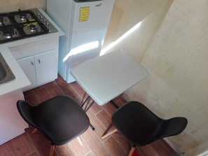 Compact kitchen with gas stove, refrigerator, and dining area.