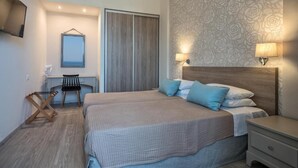 A bedroom with a bed, bedside tables, a desk, and a chair. - Icarus Suite Apartments (Rethymno)