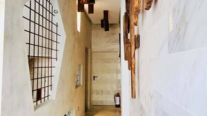A hallway with a marble floor, wooden wall decor, and a fire extinguisher. - Hotel Vacanzy Urban Boutique - Adults Only (La Oliva)