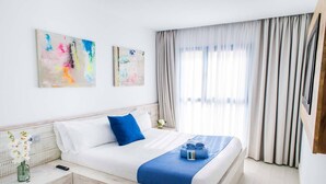 A hotel room with a bed, a nightstand, a vase with flowers, and two abstract paintings on the wall. - Hotel Vacanzy Urban Boutique - Adults Only (La Oliva)