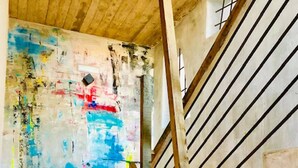 A staircase with a wooden handrail and a metal railing, leading to a room with a colorful abstract painting and a glass vase on a shelf. - Hotel Vacanzy Urban Boutique - Adults Only (La Oliva)
