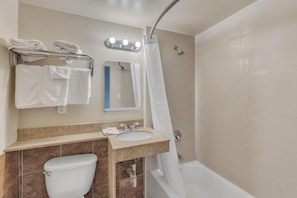 A bathroom with a toilet, sink, and shower. There are towels on a rack and a mirror above the sink. - Viking Motel (Detroit)