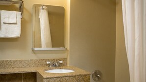 A bathroom with a toilet, sink, mirror, and shower. - Viking Motel (Detroit)