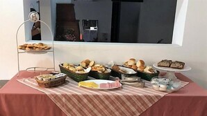 A table with various food items, including bread and pastries, arranged on a tablecloth. - Hosteria Sajonia (Villa Gesell)