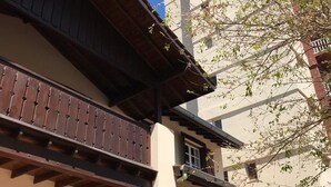 A traditional building with a wooden balcony and a modern building in the background. - Hosteria Sajonia (Villa Gesell)