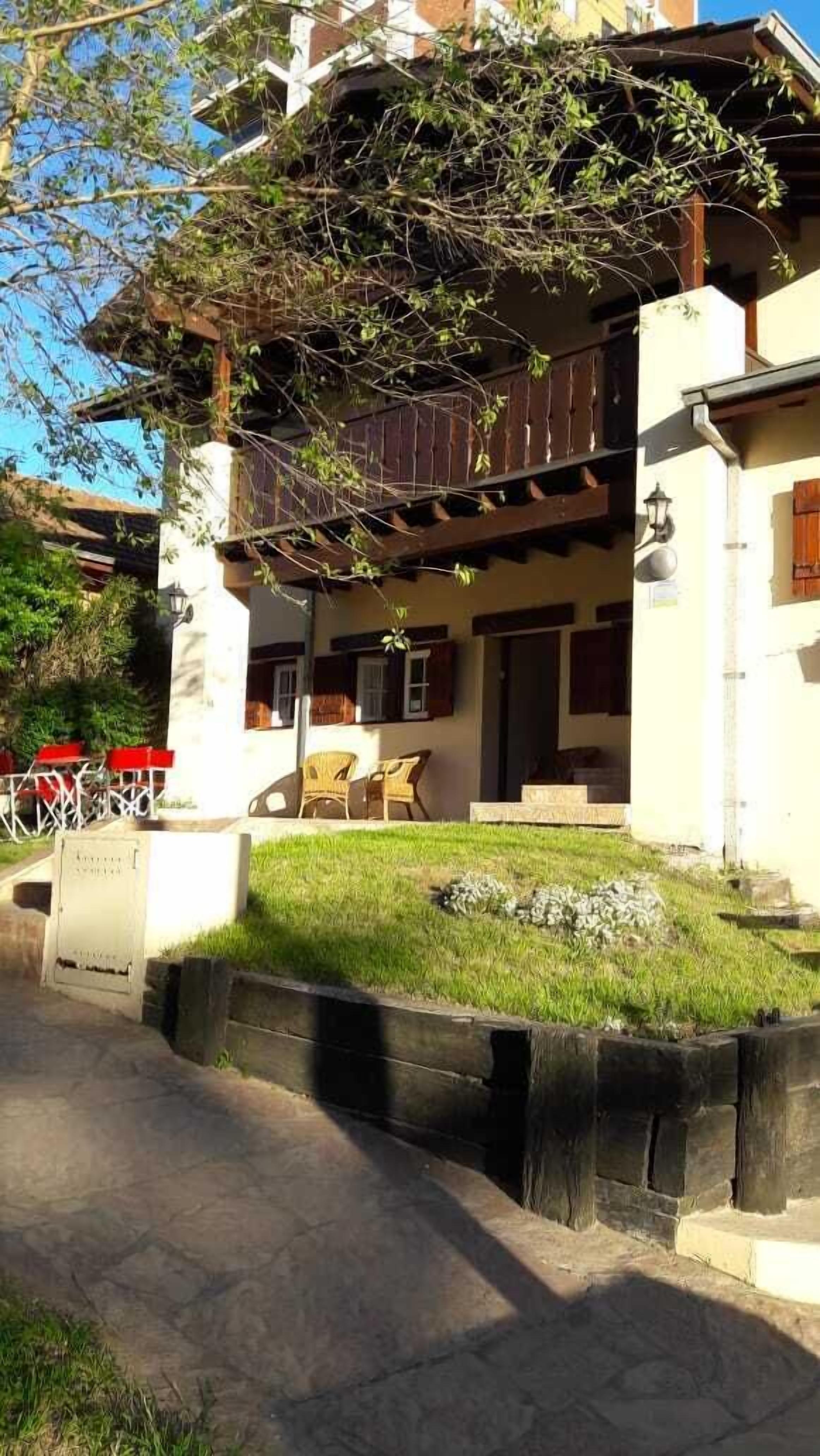 A two-story building with a balcony, outdoor seating, and a stone pathway leading to the entrance.