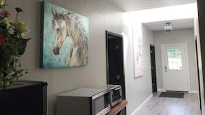 Un passadís amb un quadre penjat d'un cavall, un microones a l'estant i una porta amb un cartell que diu "UNICORNS & RAINBOWS".