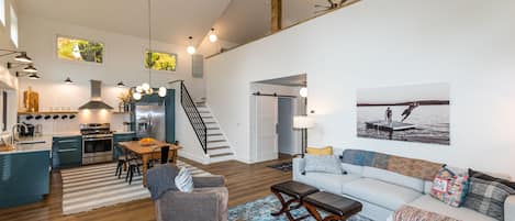A spacious living area with a kitchen, dining table, and a large window.
