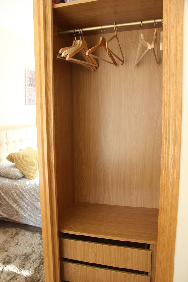 Een houten garderobe met kledingroede en lades.