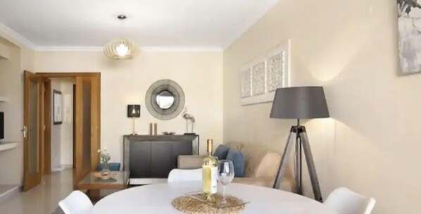Een moderne woonkamer met een ronde eettafel, een bank, een lamp en een televisie.