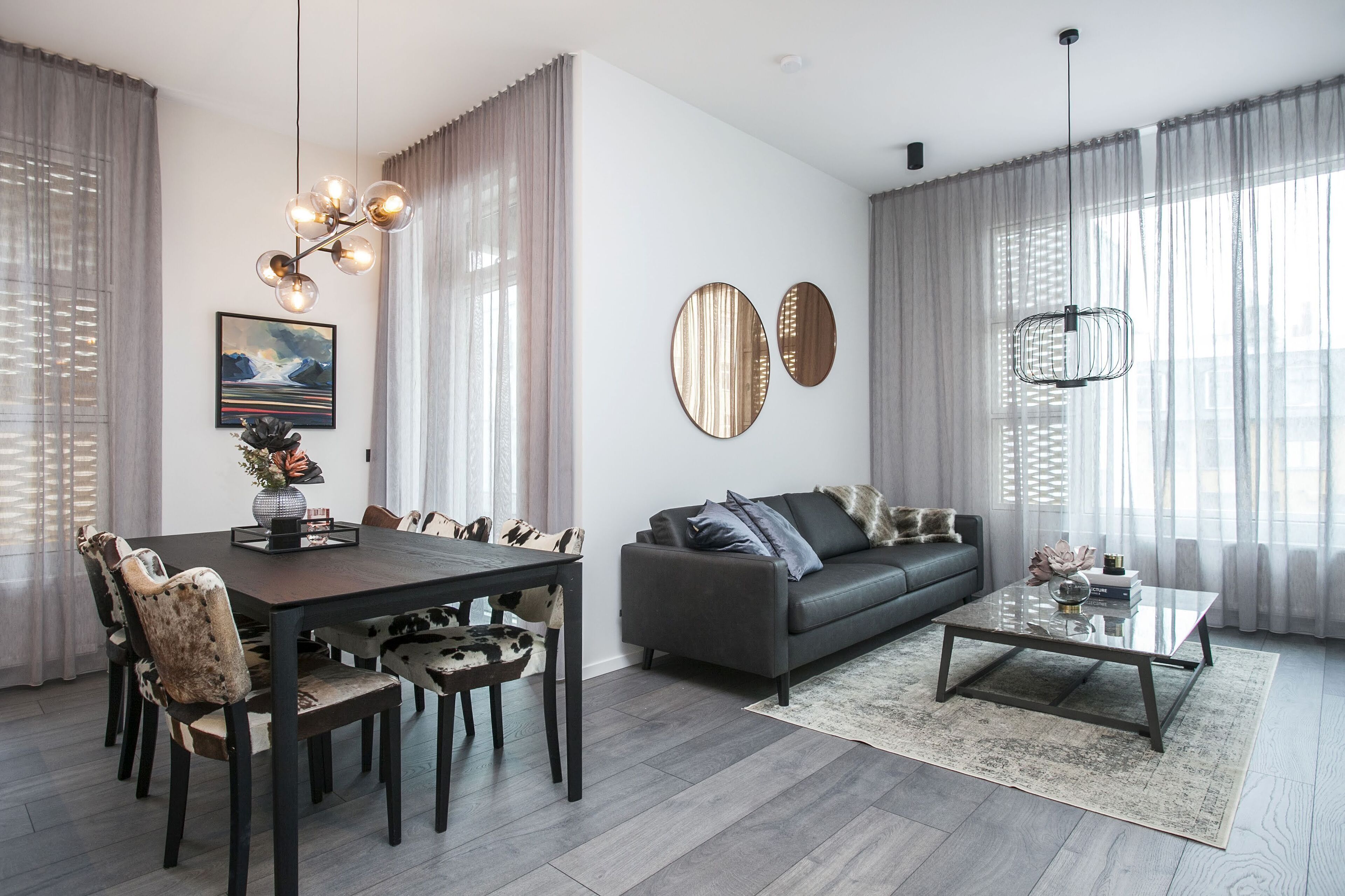 Un salon moderne avec un coin repas, comprenant une table à manger en bois foncé, un canapé gris et une table basse.