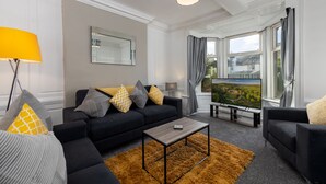 Ein modernes Wohnzimmer mit einem schwarzen Sofa, einem Holztisch und einem Fernseher auf einem Schrank.