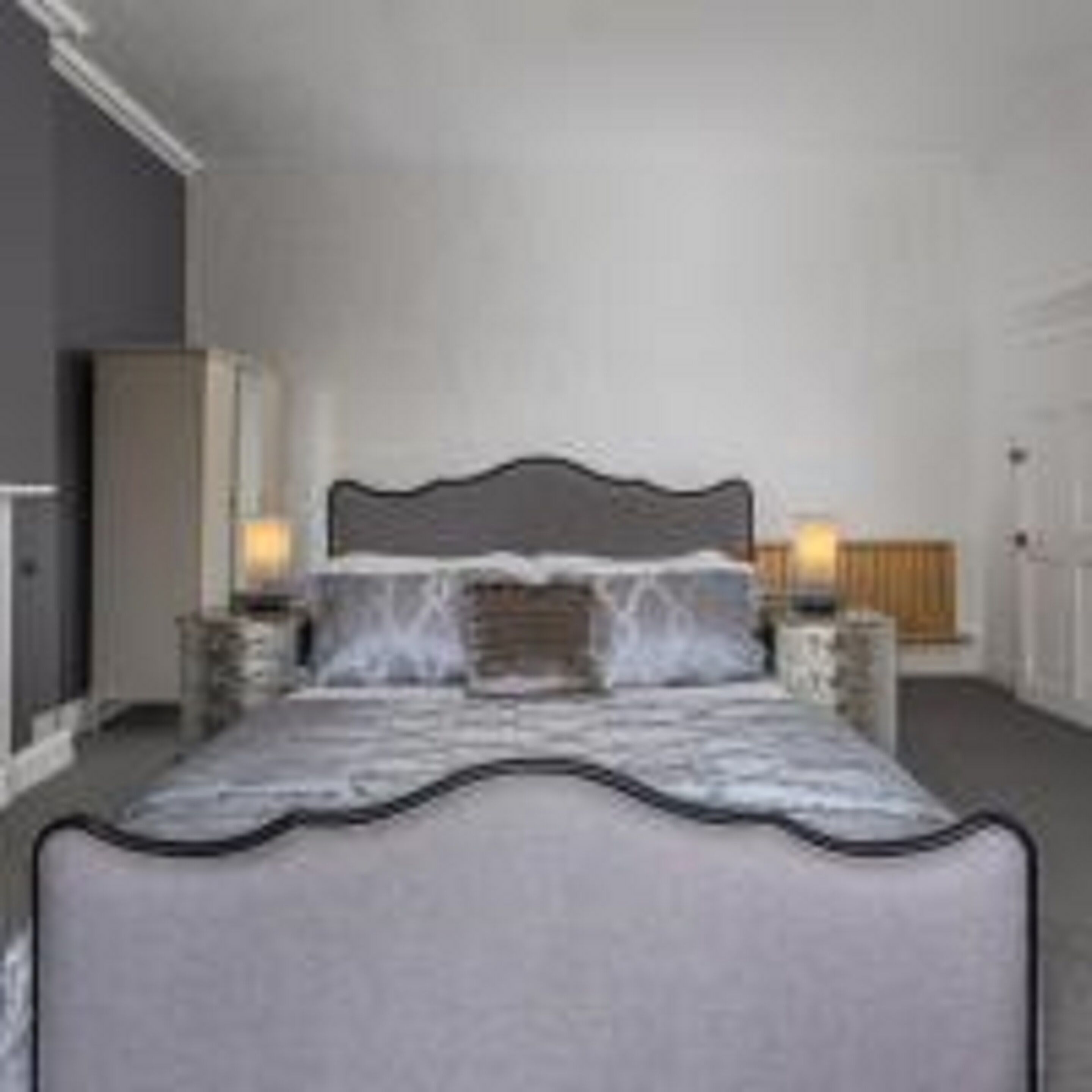 A bedroom with a large bed, two bedside tables, and a nightstand.
