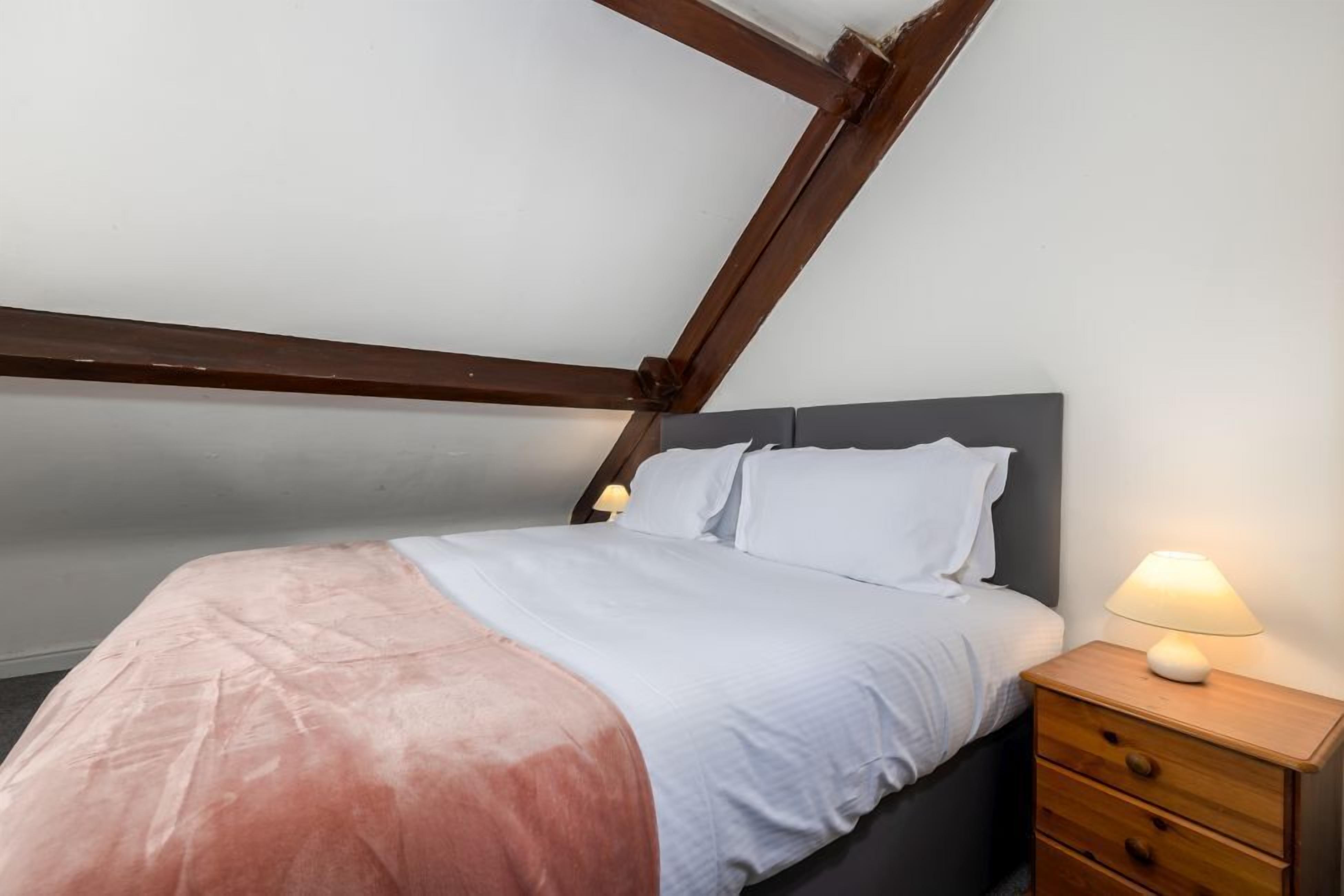 Una camera da letto con un letto, un comodino e una lampada.