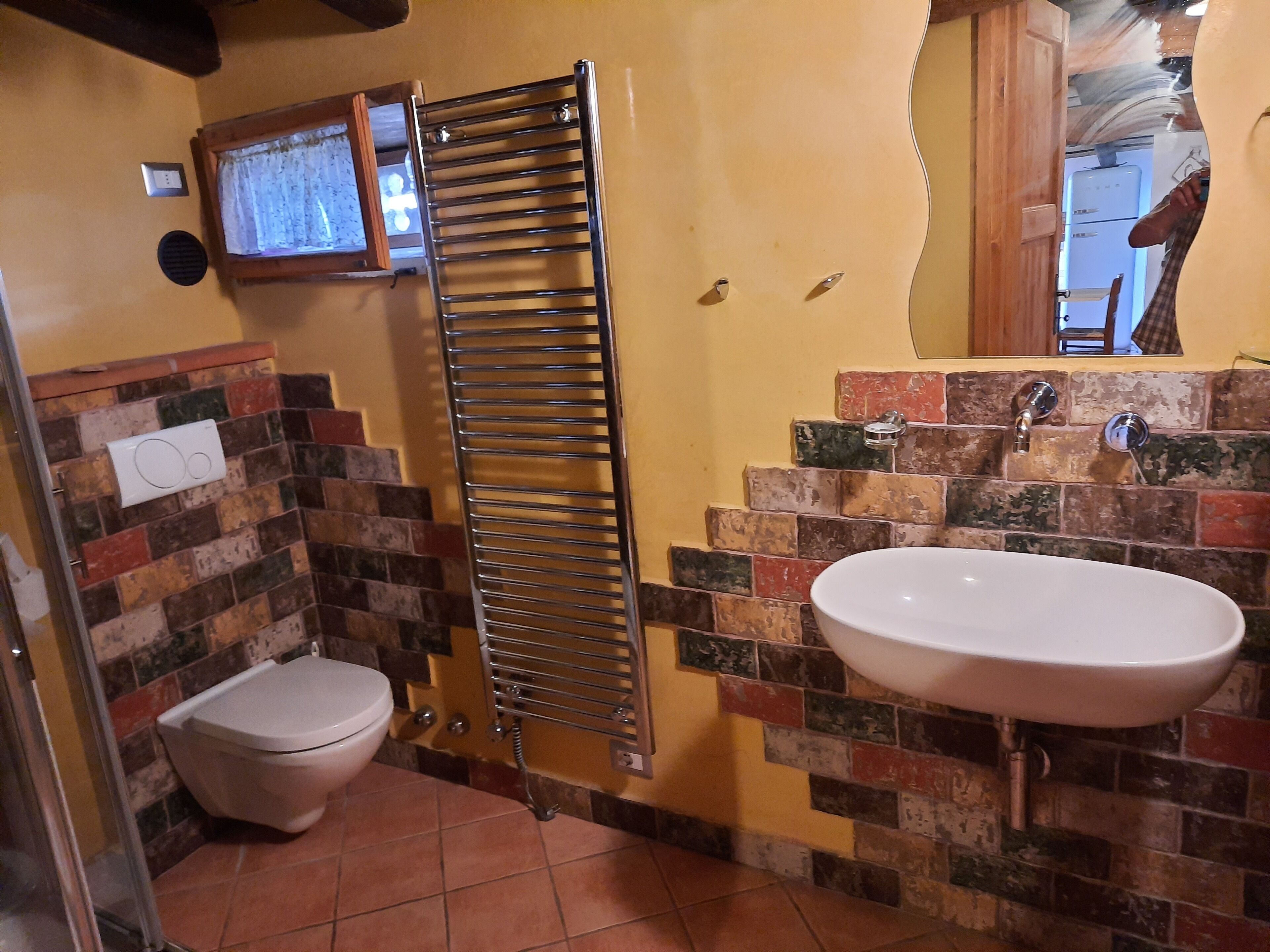 Un baño con inodoro, toallero, lavabo y pared de azulejos.